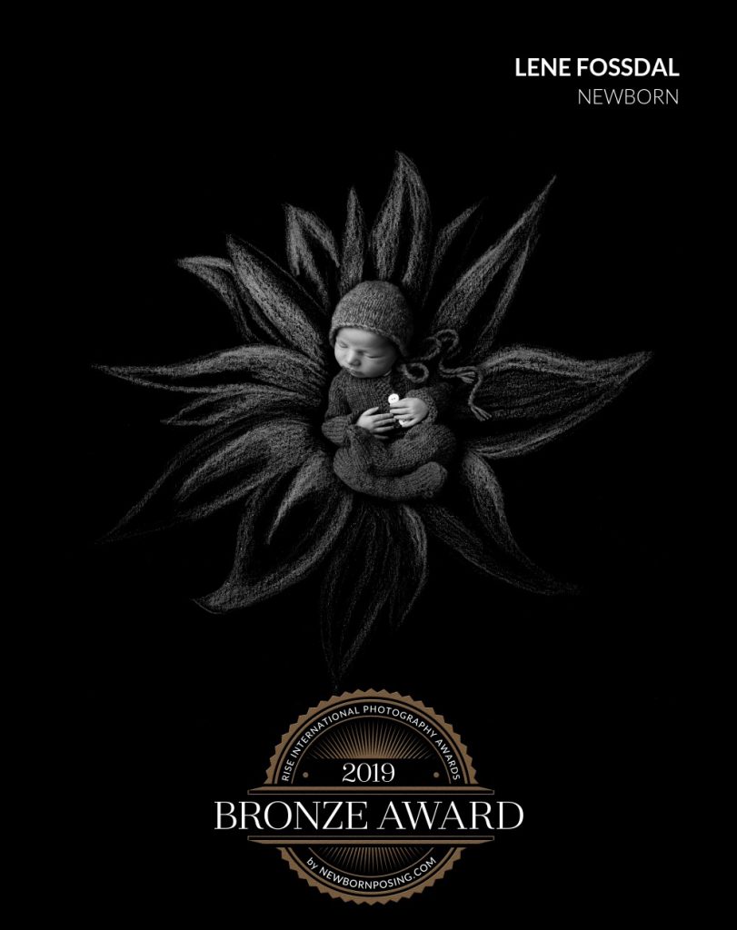 Liten baby i en tegnet blomst på svart bakgrunn. Fikk bronse i Rise Awards.